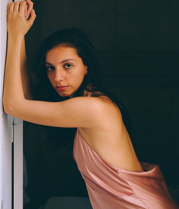 Woman in a graceful yoga pose with pink light accents.